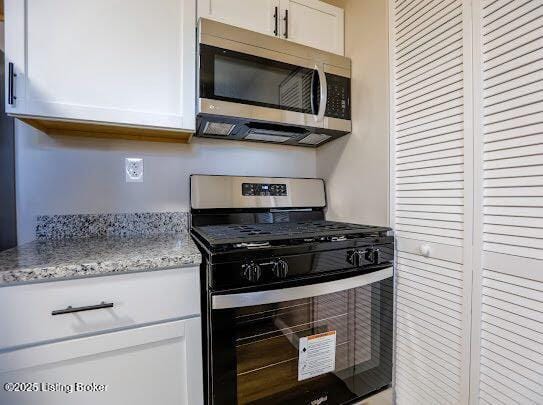 kitchen with appliances with stainless steel finishes, white cabinets, and light stone counters