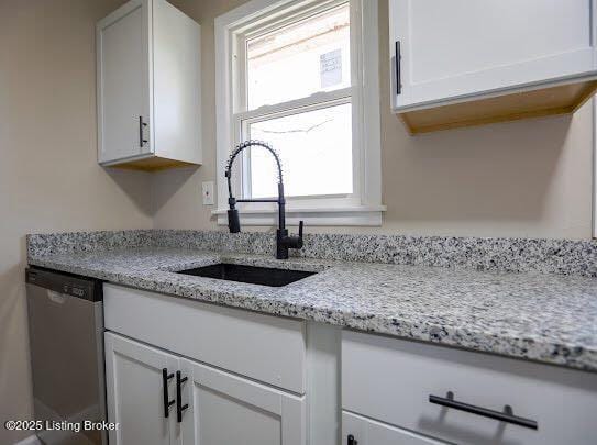 kitchen featuring white cabinetry, light stone countertops, stainless steel dishwasher, and sink