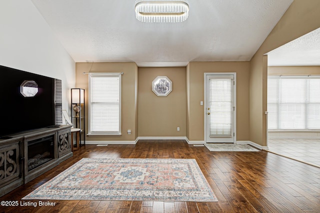 entrance foyer featuring a textured ceiling, vaulted ceiling, and dark hardwood / wood-style flooring