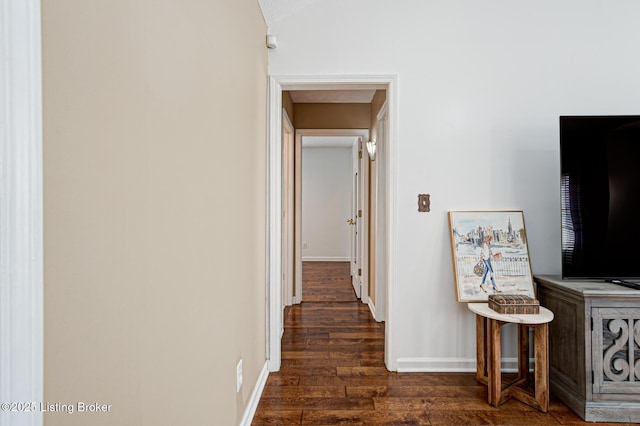 hallway with dark wood-type flooring and vaulted ceiling