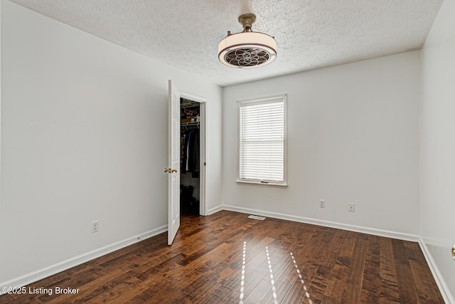 unfurnished room with dark wood-type flooring and a textured ceiling