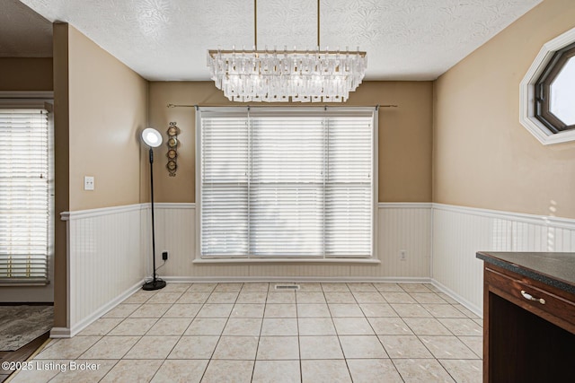 unfurnished dining area featuring a textured ceiling and light tile patterned floors