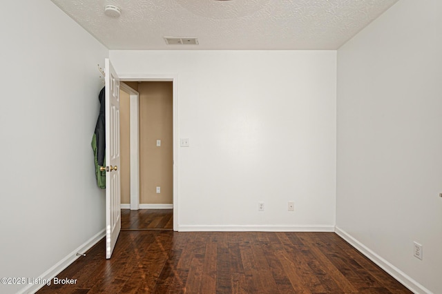 empty room with dark hardwood / wood-style flooring and a textured ceiling