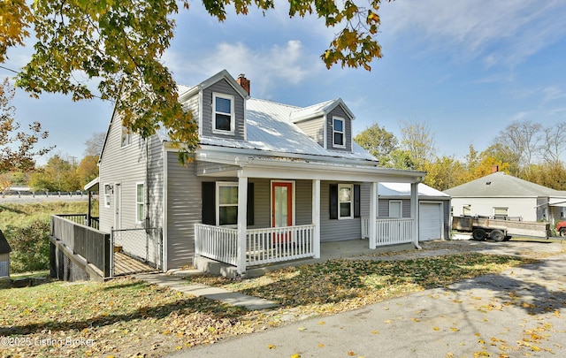 cape cod home with a garage, an outdoor structure, and covered porch