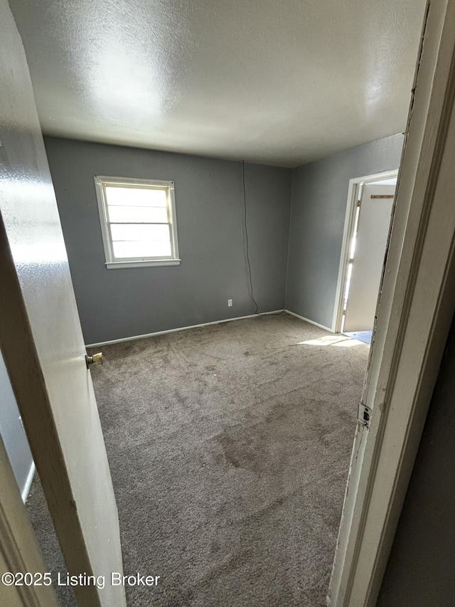 carpeted spare room with a textured ceiling