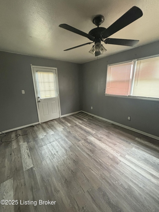 spare room with ceiling fan, hardwood / wood-style flooring, a wealth of natural light, and a textured ceiling