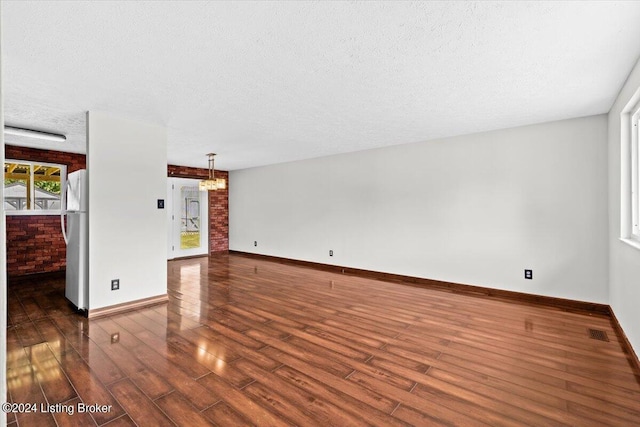 unfurnished living room featuring dark hardwood / wood-style flooring, a chandelier, and a textured ceiling