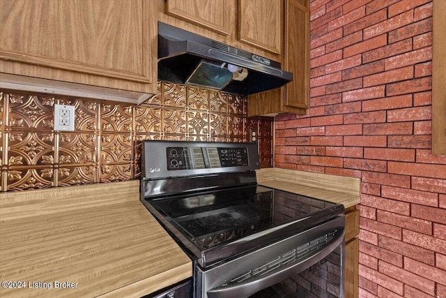 kitchen with stainless steel range with electric stovetop and brick wall