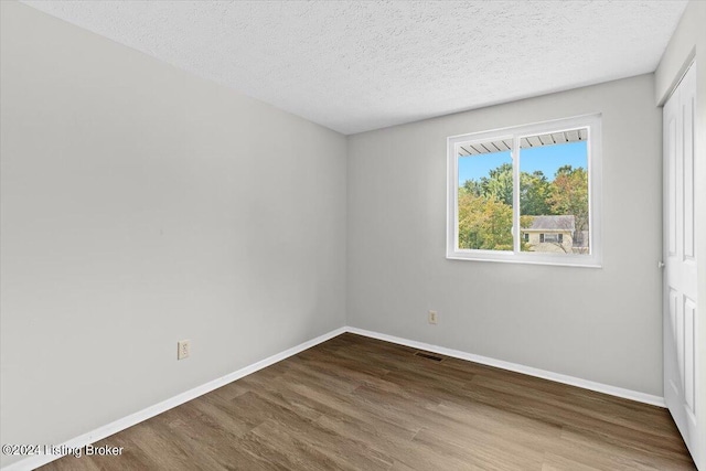 spare room featuring hardwood / wood-style floors and a textured ceiling