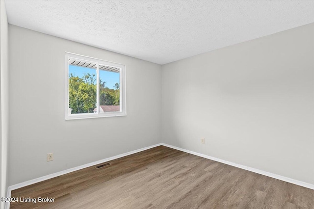 empty room featuring hardwood / wood-style flooring and a textured ceiling