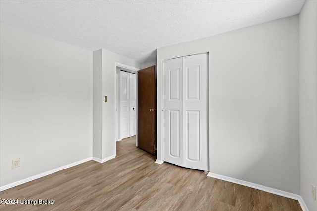 unfurnished bedroom with a textured ceiling and light wood-type flooring