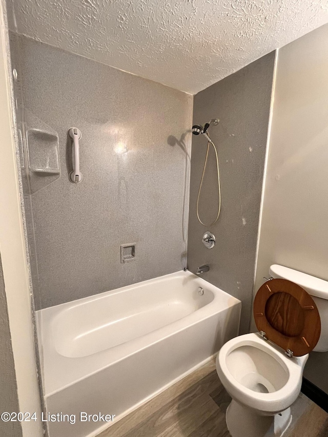 bathroom featuring shower / bathtub combination, wood-type flooring, toilet, and a textured ceiling