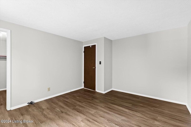 empty room featuring dark hardwood / wood-style floors and a textured ceiling