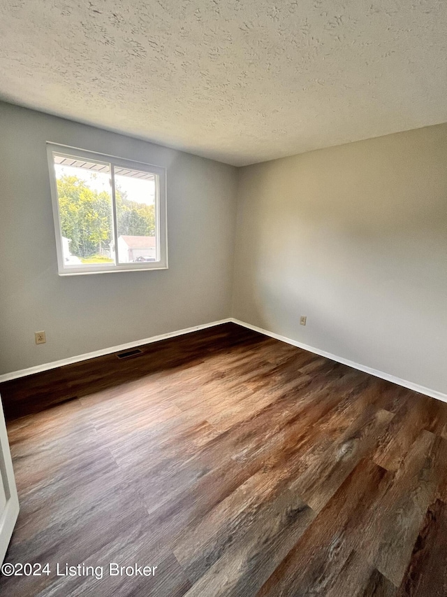 unfurnished room with hardwood / wood-style floors and a textured ceiling