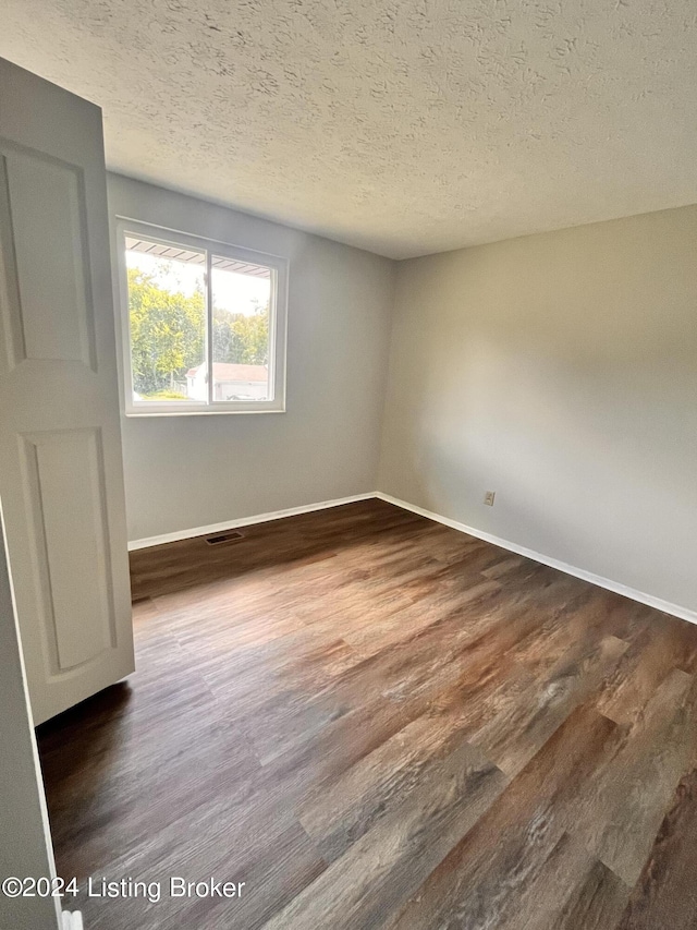 empty room featuring dark hardwood / wood-style flooring and a textured ceiling