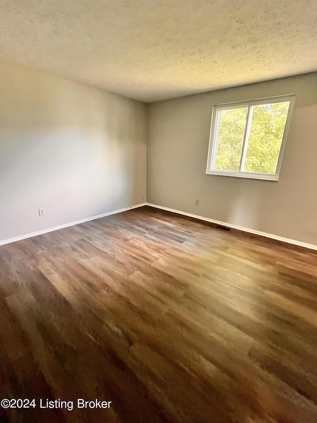 unfurnished room with dark wood-type flooring and a textured ceiling