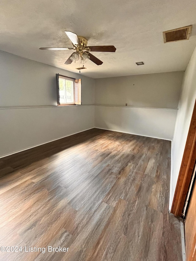 unfurnished room with dark wood-type flooring, a textured ceiling, and ceiling fan