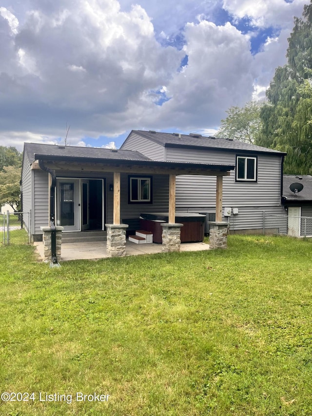 rear view of property featuring a hot tub, a patio, a yard, and cooling unit