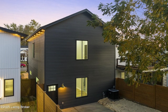 back house at dusk with cooling unit and a patio area