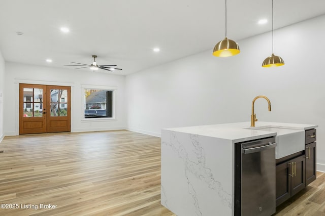 kitchen featuring an island with sink, dishwasher, pendant lighting, and light hardwood / wood-style flooring