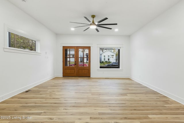 spare room with a healthy amount of sunlight, light hardwood / wood-style floors, and french doors