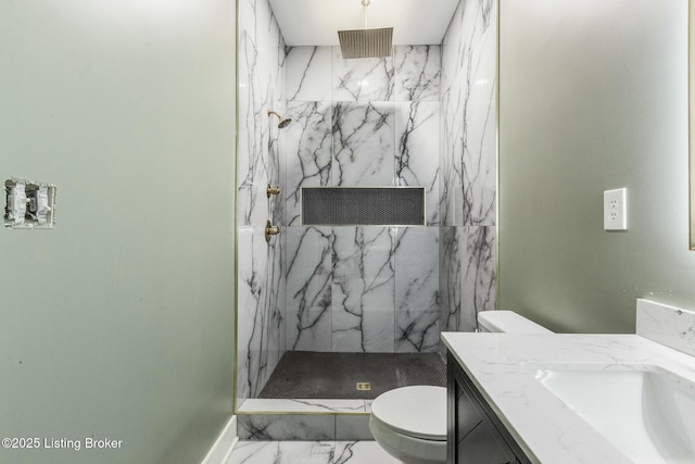 bathroom with vanity, tiled shower, and toilet