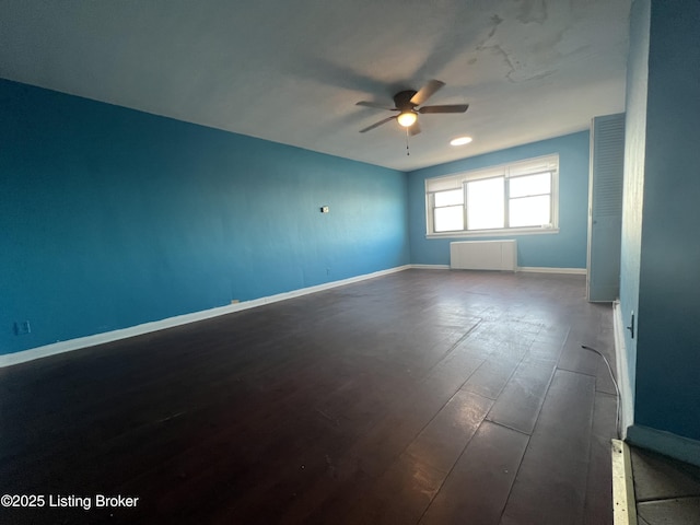 empty room featuring hardwood / wood-style flooring, ceiling fan, and radiator