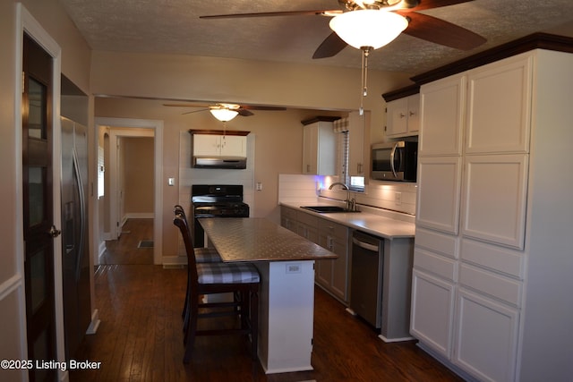 kitchen with sink, white cabinetry, stainless steel appliances, dark hardwood / wood-style floors, and a textured ceiling