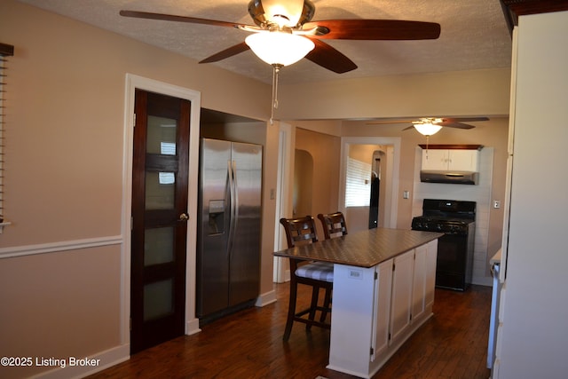 kitchen featuring stainless steel fridge, a breakfast bar, white cabinetry, a kitchen island, and black range with gas stovetop