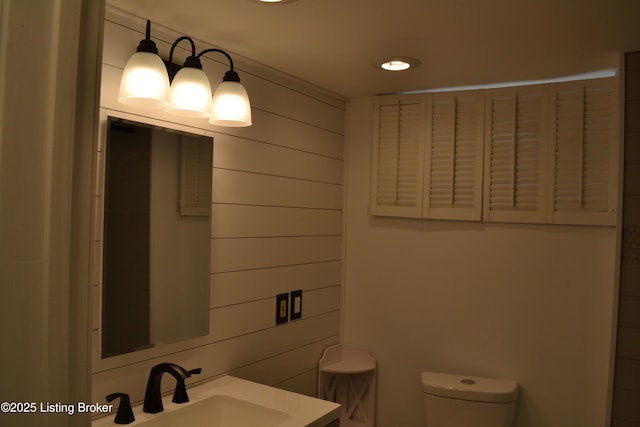 bathroom featuring vanity, toilet, and wood walls