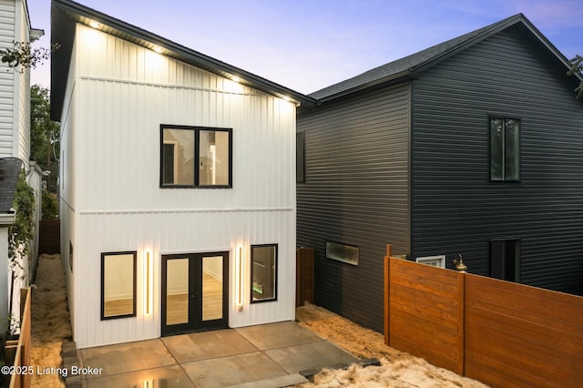 back house at dusk featuring a patio and french doors