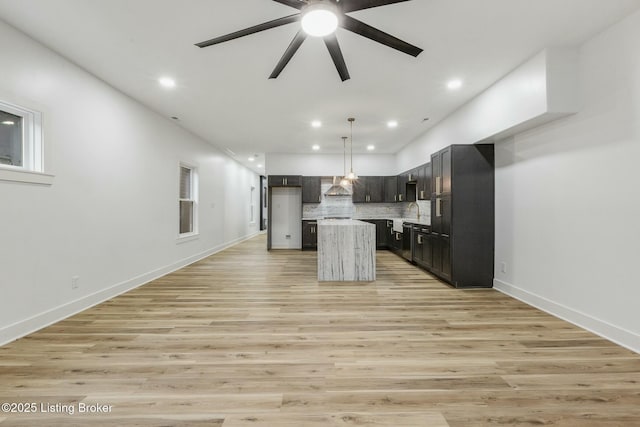 kitchen featuring tasteful backsplash, decorative light fixtures, a center island, and light hardwood / wood-style floors