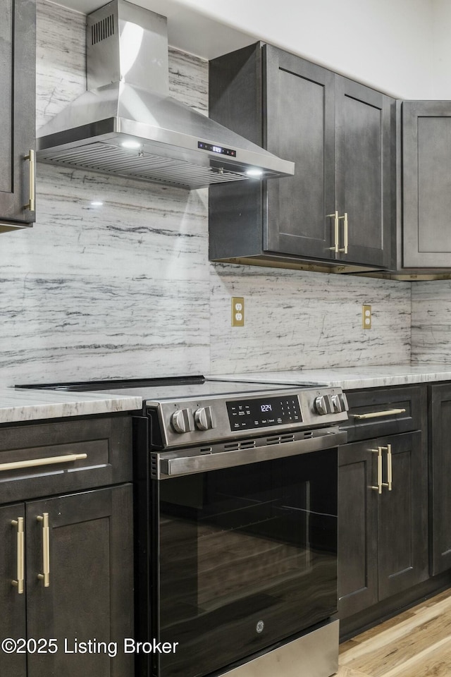 kitchen featuring tasteful backsplash, light hardwood / wood-style flooring, wall chimney exhaust hood, and stainless steel electric range oven