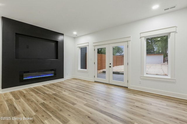 unfurnished living room with french doors and light hardwood / wood-style floors