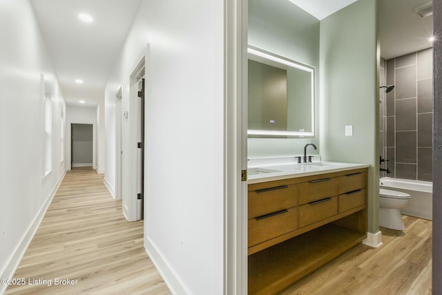 full bathroom with vanity, hardwood / wood-style flooring, tiled shower / bath combo, and toilet