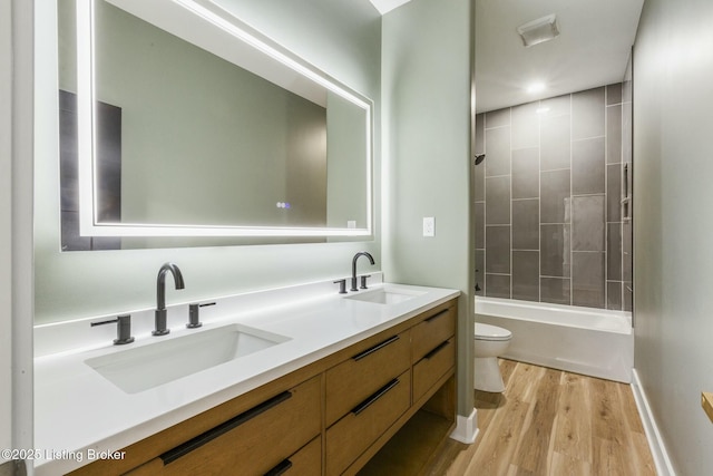 full bathroom with vanity, toilet, tiled shower / bath combo, and hardwood / wood-style floors