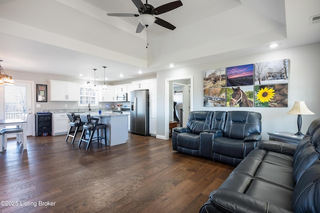 living room featuring wine cooler, dark hardwood / wood-style floors, a raised ceiling, and ceiling fan