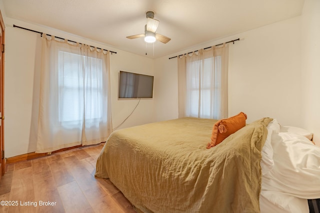 bedroom featuring multiple windows, light hardwood / wood-style floors, and ceiling fan