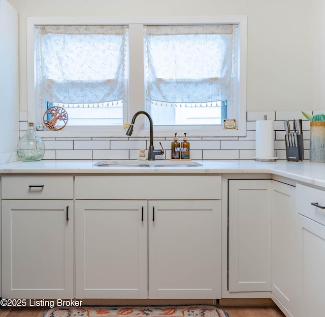 kitchen featuring white cabinetry, sink, and backsplash