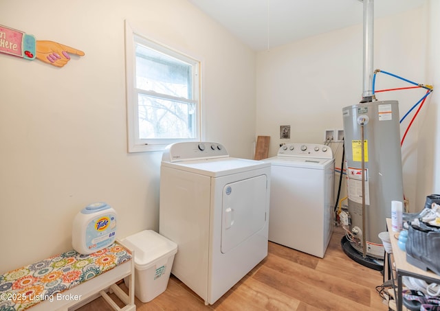 clothes washing area with gas water heater, light hardwood / wood-style flooring, and washing machine and dryer