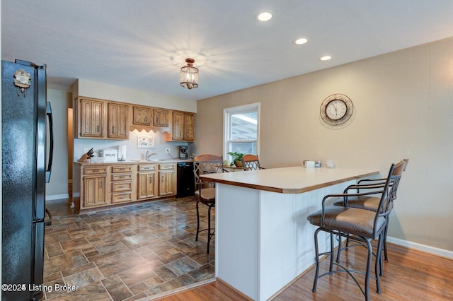 kitchen featuring a breakfast bar, sink, dark hardwood / wood-style flooring, kitchen peninsula, and black appliances