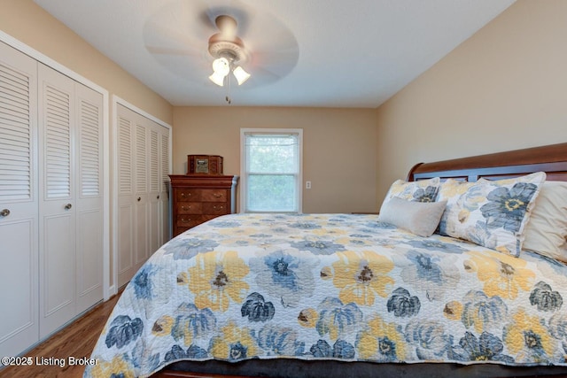 bedroom featuring multiple closets, hardwood / wood-style flooring, and ceiling fan