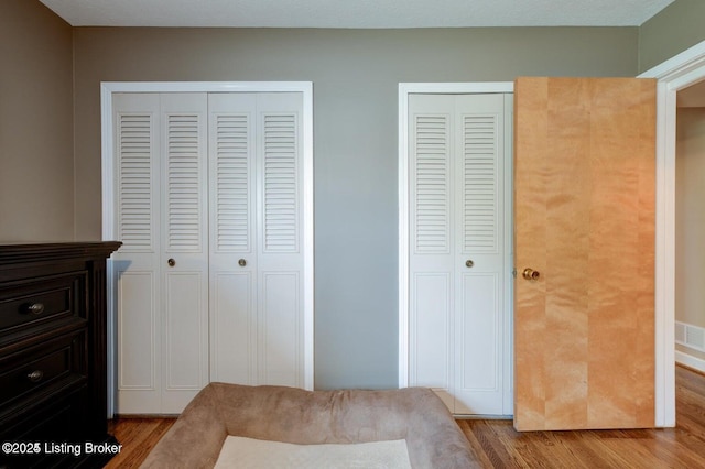 bedroom featuring multiple closets and light hardwood / wood-style flooring