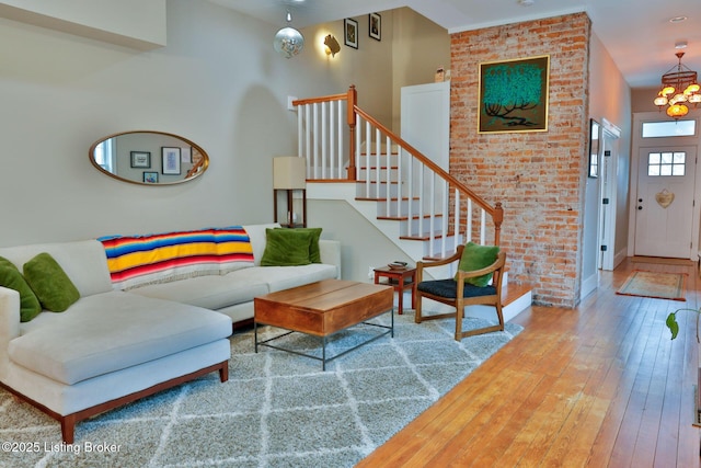 living room featuring hardwood / wood-style flooring, brick wall, and an inviting chandelier