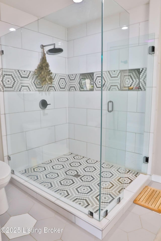 bathroom featuring tile patterned floors, a shower with door, and toilet