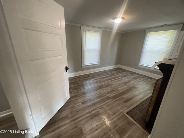 spare room featuring crown molding, dark wood-type flooring, and a wealth of natural light