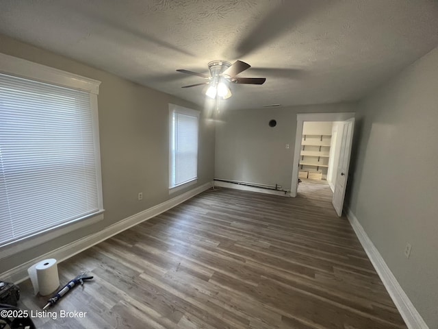 spare room with ceiling fan, hardwood / wood-style floors, a textured ceiling, and a baseboard heating unit