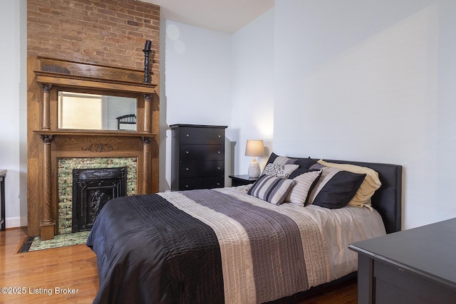 bedroom featuring a tile fireplace and dark wood-type flooring