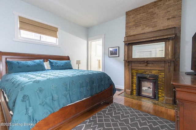 bedroom with a large fireplace and hardwood / wood-style floors