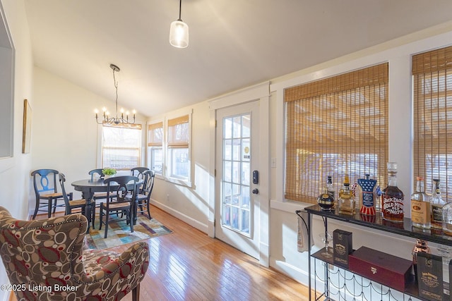 dining room featuring lofted ceiling, a chandelier, and light hardwood / wood-style floors